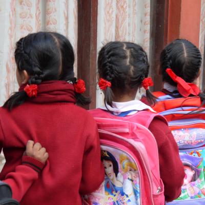 Students in Nepal wait patiently in a line for their Childcare volunteer Children line up with their backpacks outside their classroom in Nepal